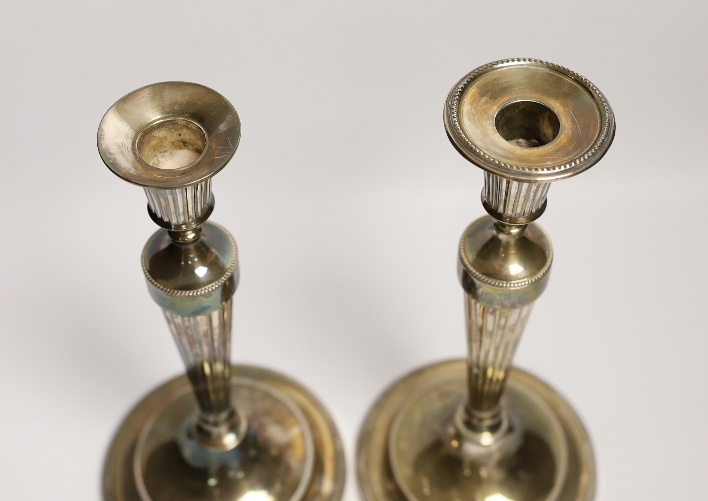 A pair of George III silver candlesticks, with waisted fluted stems, John Winter & Co, Sheffield, date letter rubbed, circa 1780, height 30cm, weighted, lacking one sconce.